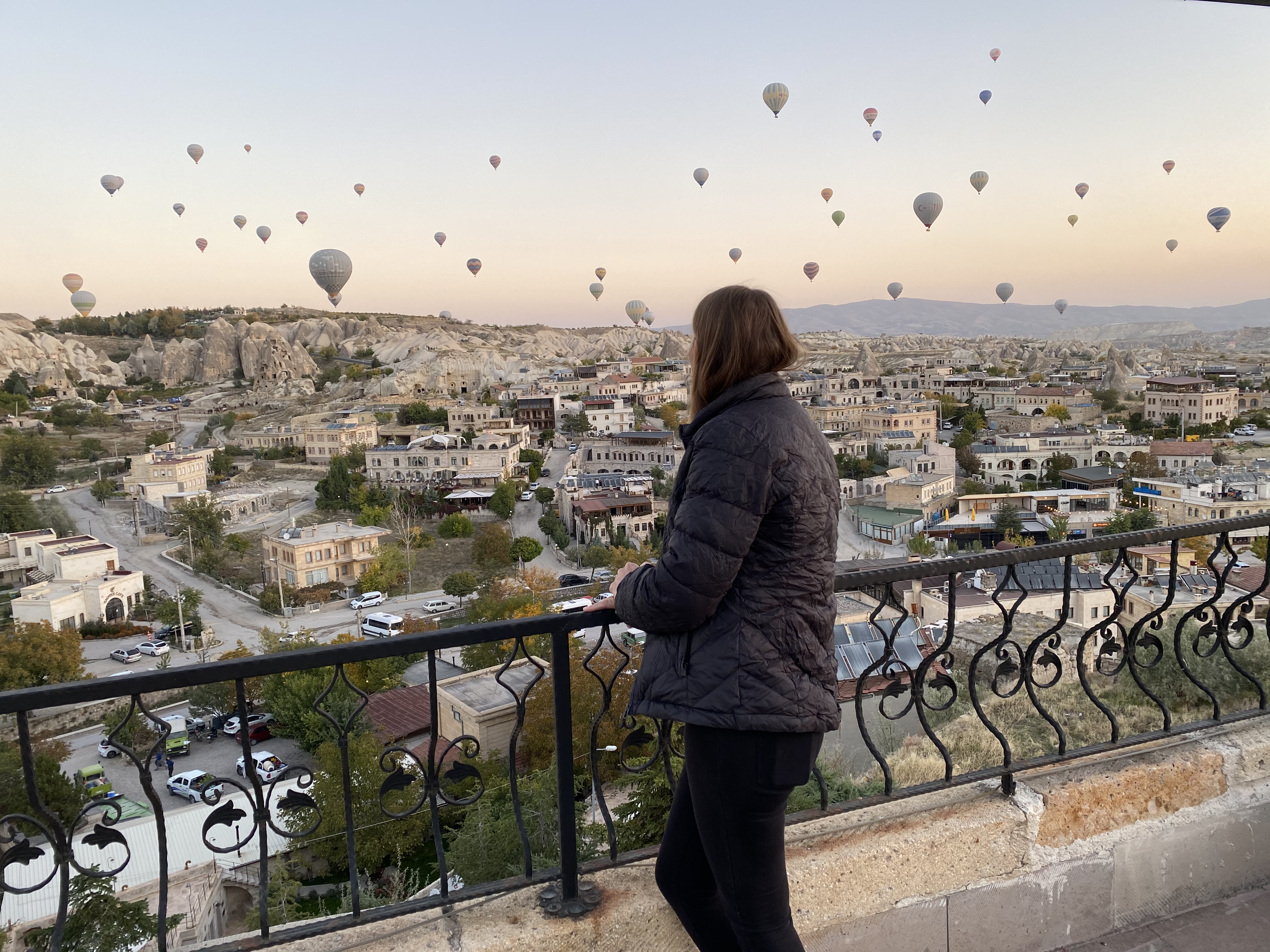 Melissa Wiringi on a Göreme balcony watching hot air balloons rise over Cappadocia at sunrise